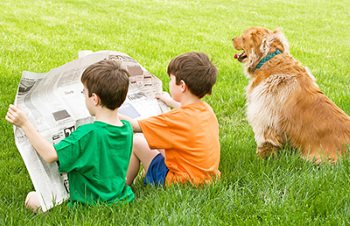 Two boys sitting on the lawn reading the newspaper