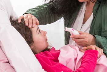 Parent checking temperature of sick child